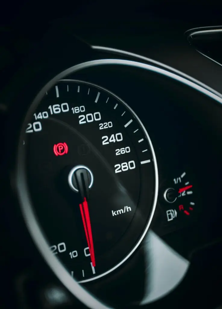 Detailed close-up of a speedometer with red needle indicating speed in km/h.